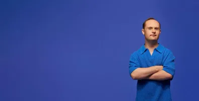 Man standing with arms crossed in front of a blue background.