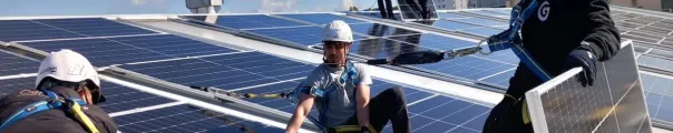 Men installing solar panels on top of a roof